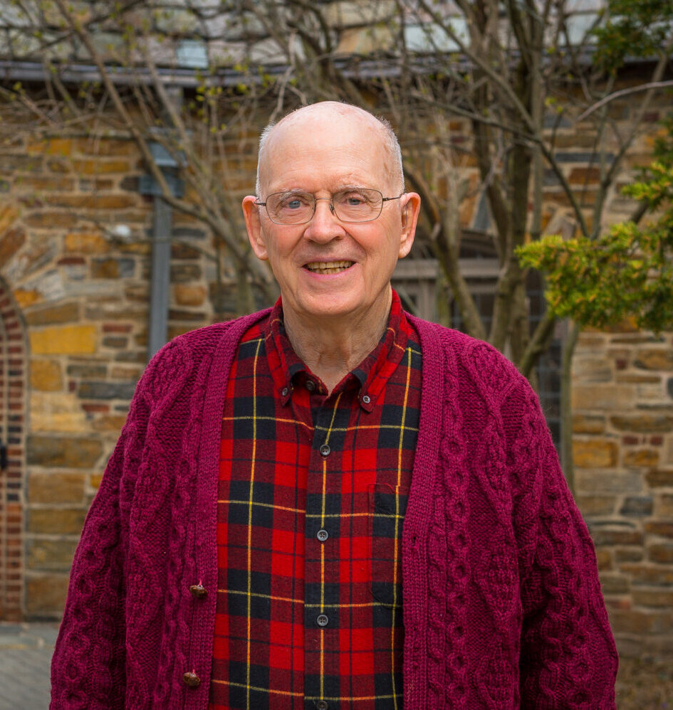 Senior man in red plaid shirt smiling for a photo outside