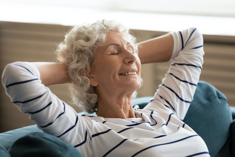 A happy senior woman relaxing on the couch, free from stress.