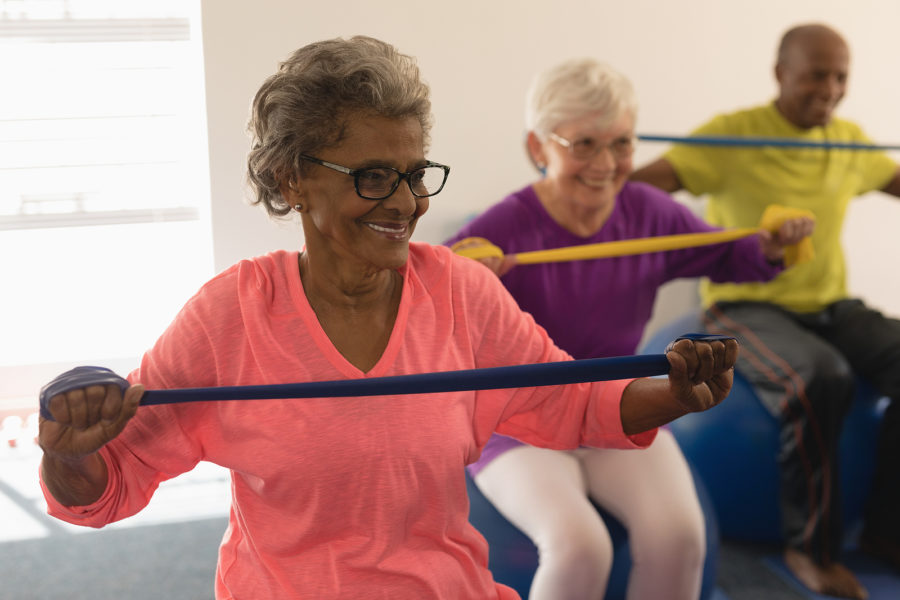 A group of seniors exercise with colorful fitness bands.