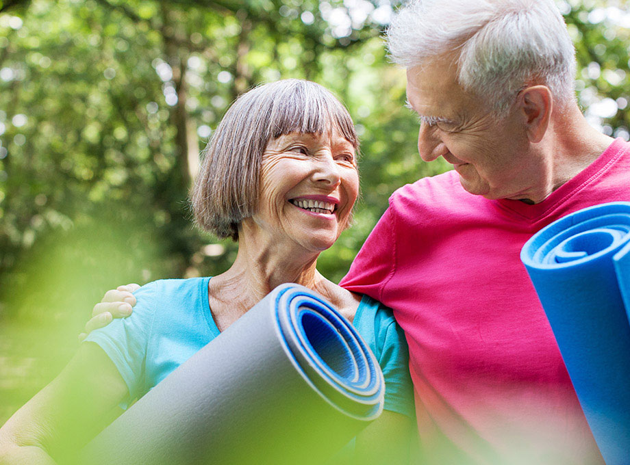 A senior couple with rolled up exercise mats