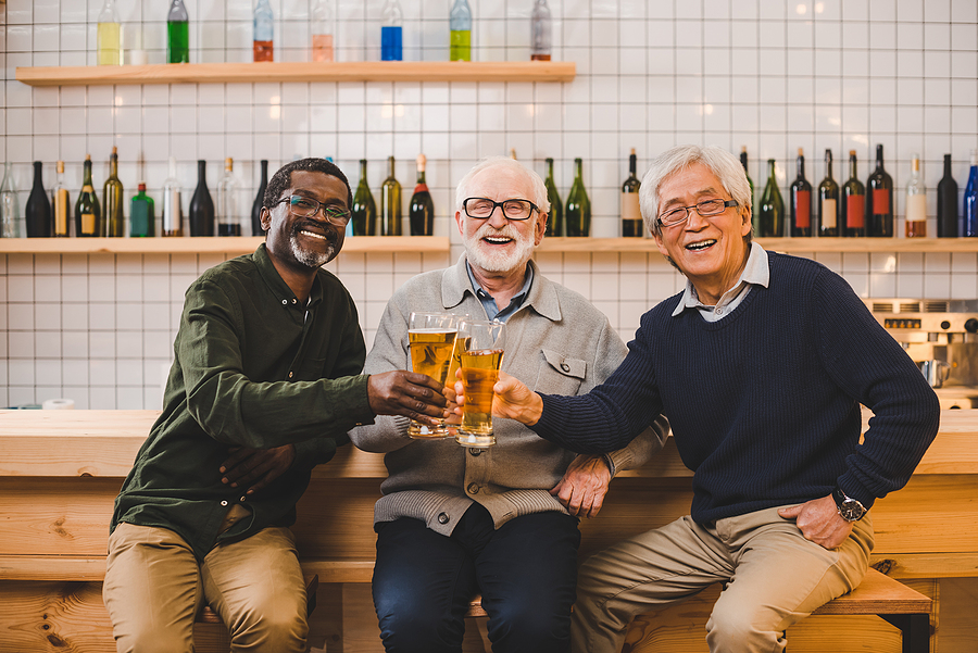 Group of elderly men drinking beer together at a brewery.