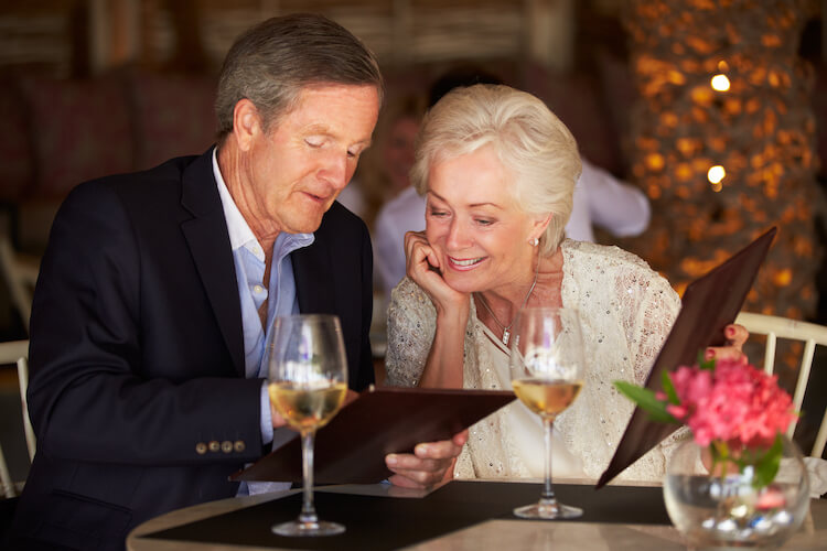 Senior couple looking at dinner menu at a table.