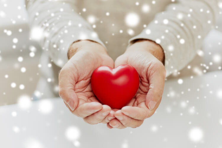 Senior man holding a heart in an image representing charity.