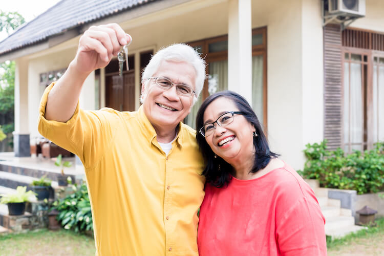 Senior couple in front of their recently sold house.