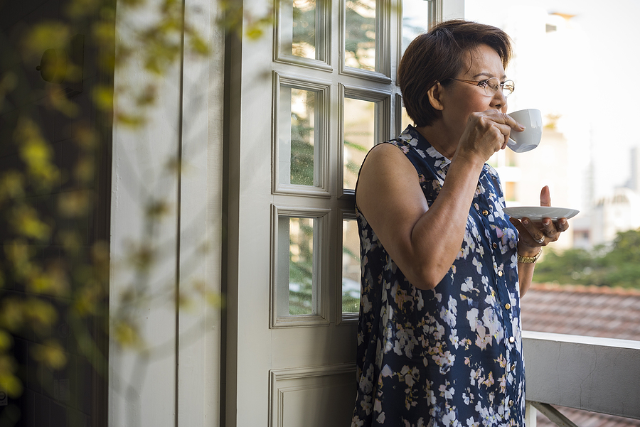 A senior woman drinks tea while looking outside