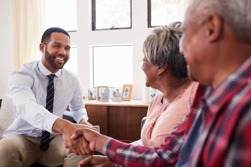 A senior couple shake hands with a financial advisor