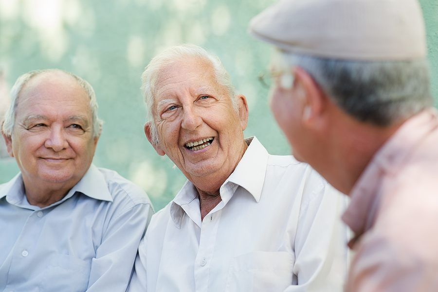 Three older adult men are sitting and talking together