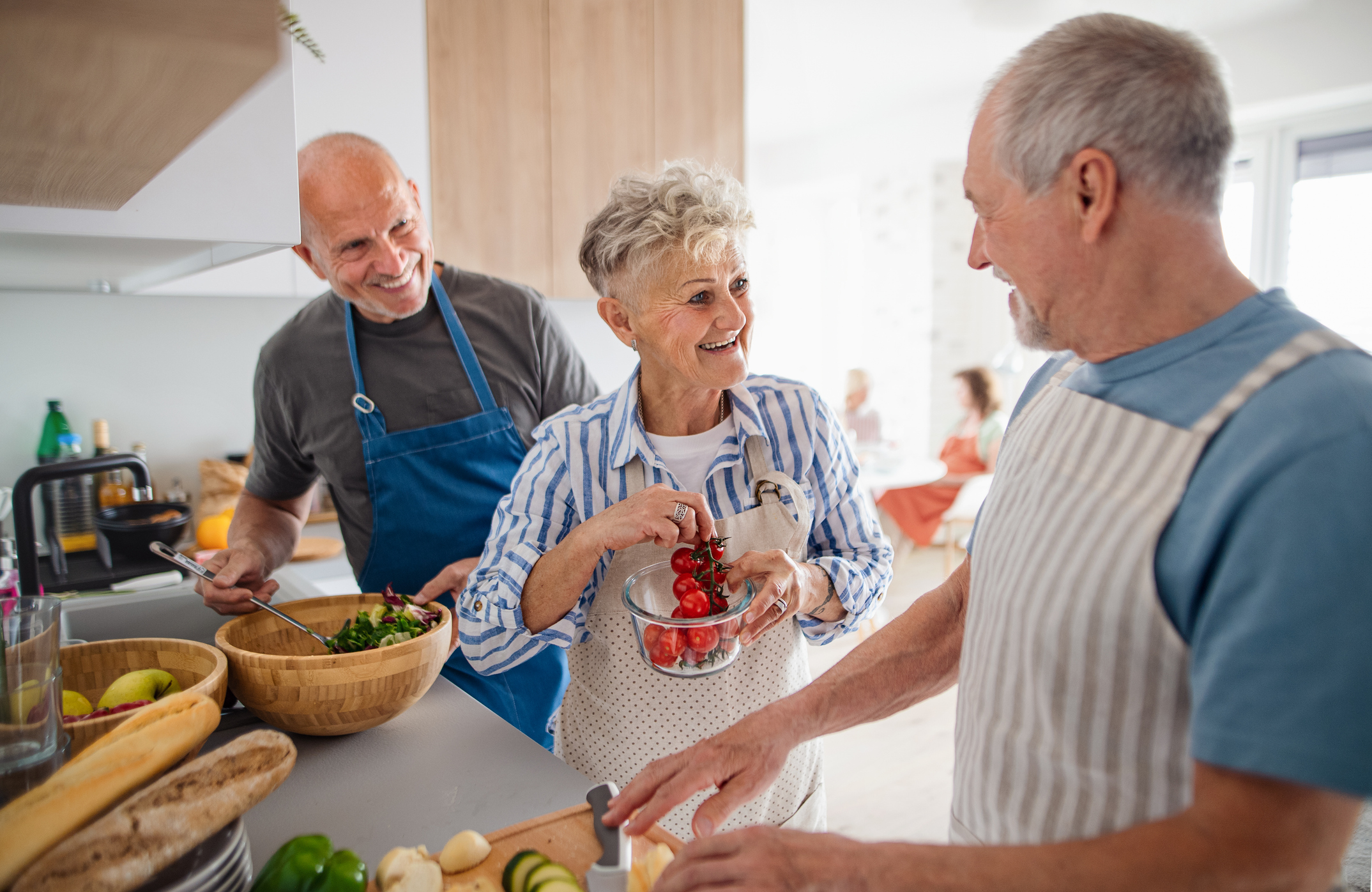 A group of seniors makes a salad together in a kitchen
